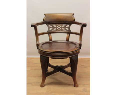 Early 20th century mahogany revolving desk chair, with bowed back centred by pierced panel, saddle seat on cabriole legs and 