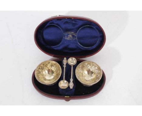 Pair of Victorian silver salts of circular form, with embossed decoration, bead borders and matching spoons, in a Garrards fi