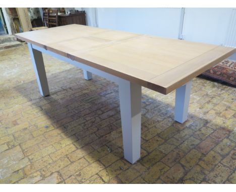 A Neptune style dining table with two leaves which fold into the table - 230cm extended by 90cm but can be reduced to 168cm w