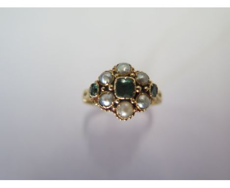 A Victorian 18ct emerald and split pearl cluster ring, fully engraved shank and scroll shoulders to a centre mixed cut emeral