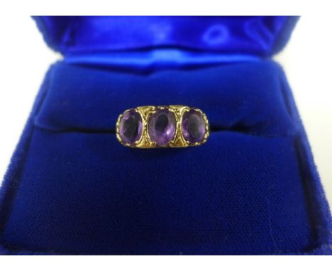 Vintage three stone amethyst dress ring, set to a scrolling yellow metal band, UK ring size K