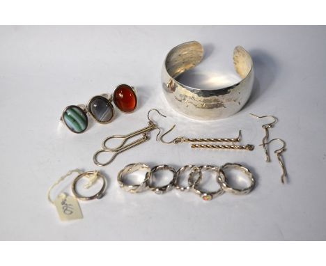 A collection of silver and white metal jewellery including a contemporary hammered silver open bangle, three pairs of earring