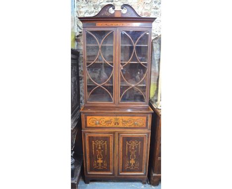 A Sheraton Revival marquetry inlaid satinwood and walnut secretaire bookcase, the broken swaneck pediment over a pair of astr