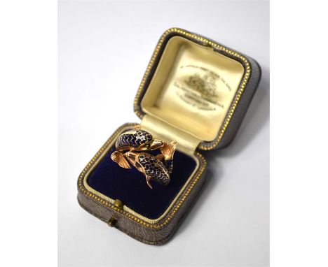 A Continental yellow metal ring formed of two conjoined dolphins with blue enamel decoration and cabochon stone set eyes, sta