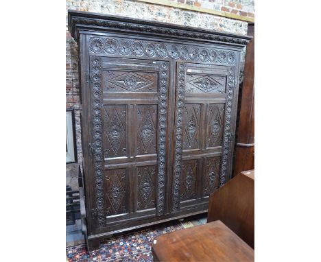 A substantial antique 17th century style jointed oak livery cupboard with carved and moulded decoration, the two doors enclos