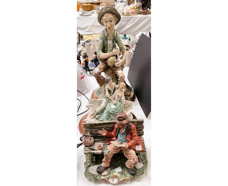 A Capodimonte bisque figure tramp reading on bench, signed R. Guidolin, hand painted, length 22cm, A Resin Capodimonte group 
