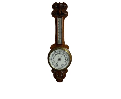 An oak cased aneroid barometer with carved relief c1930, with an 8” porcelain dial measuring atmospheric air pressure from 26