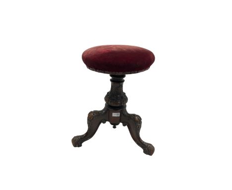 Victorian carved piano stool. the swivel seat upholstered in red fabric over carved column leading into three carved supports