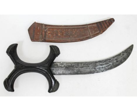 An African beja hadendoa dagger with ebony X section handle, curved blade and leather scabbard, length 33cm.  