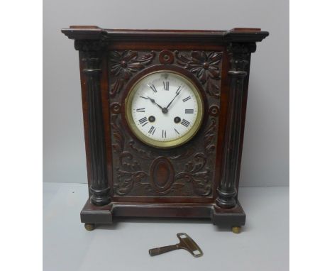 A carved walnut mantel clock 