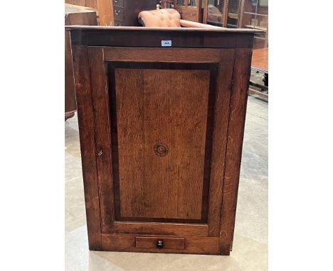 A George III oak and mahogany banded hanging corner cupboard with fitted drawer, enclosed by a rosette inlaid panel door. 43½