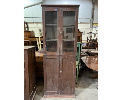 An early 20th century decorated pine cupboard enclosed by a pair of glazed doors over a pair of panel doors on plinth support