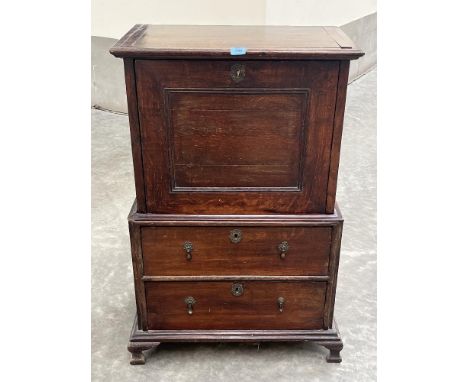 An 18th century oak cabinet on chest in two parts, the upper with fall front enclosing pigeon holes (formerly with drawers) a