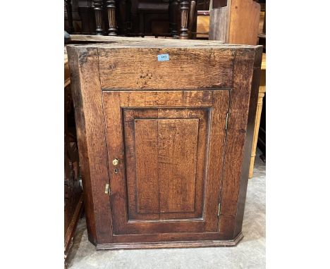 A Georgian oak hanging corner cupboard, the panel door enclosing two shaped shelves. 34½' high. Losses