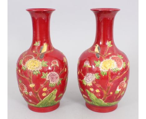 A PAIR OF CHINESE FAMILLE ROSE RED GROUND MOULDED PORCELAIN VASES, each base with a moulded Qianlong seal mark, 9.25in high.