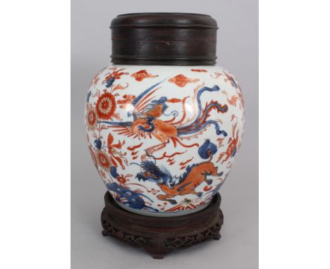 A CHINESE IMARI KANGXI PERIOD PORCELAIN JAR, circa 1700, together with a wood stand and cover, the sides of the jar painted w