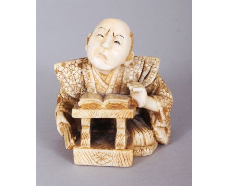 A SIGNED JAPANESE MEIJI PERIOD IVORY NETSUKE OF A SEATED SAMURAI, his face grimacing above an open book on a lectern, the bas