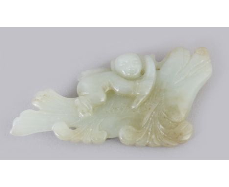 A CHINESE CELADON JADE CARVING OF A BOY RIDING A DRAGON FISH, 2.8in wide.