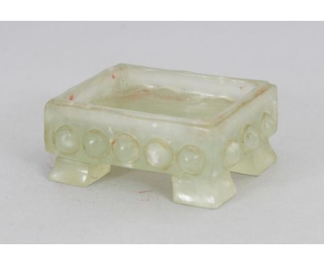A SMALL CHINESE CELADON JADE RECTANGULAR BRUSHWASHER OR STAND, the sides carved with studs, 1.6in x 1.3in x 0.7in high.