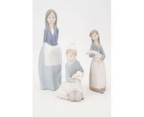 Two Lladro figurines, modelled as a girl holding a piglet and a crouching boy holding a lamb, together with a Nao figurine of