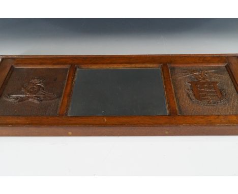 A wall or over-mantel mirror, the carved oak frame of which bearing relief representations of Royal Artillery and Army Ordnan