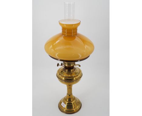 A brass oil lamp and amber shade, 63 cm high