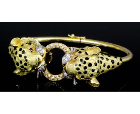 A modern 18ct white and yellow gold black enamel, ruby and diamond set twin head panther pattern stiff bangle, the heavily ca