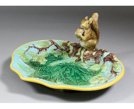 A George Jones majolica squirrel nut dish of shaped outline, painted in greens, browns, turquoise and with yellow rim, 9.5ins