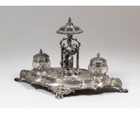 A late 19th Century French silvery metal ovoid inkstand of shaped and moulded outline, the centre with cast seated classical 