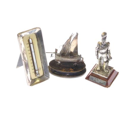 White metal figure of a soldier, silver mounted desk thermometer and a foreign silver model of a boat (3)