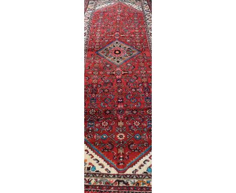 A large Iranian runner, modern, with multi-coloured ground over red field, 389 x 110cm