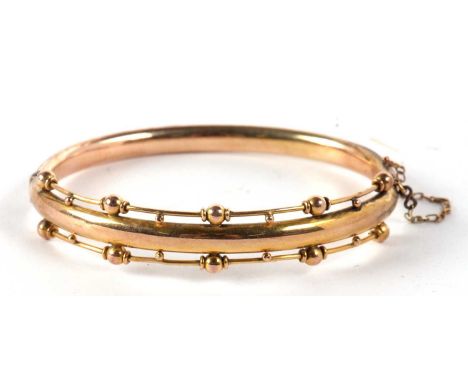 A late Victorian Etruscan style hinged bangle, the upper half with plain centre section and set to either side with a row of 