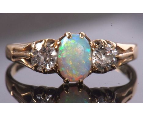 An opal and diamond ring, the oval opal set to either side with an old round brilliant cut diamond, total weight of diamonds 