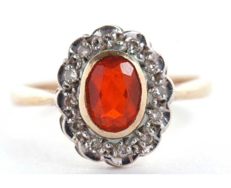 A 9ct fire opal and diamond ring, the oval fire opal in rubover mount, surrounded by small round diamonds, with plain band ha