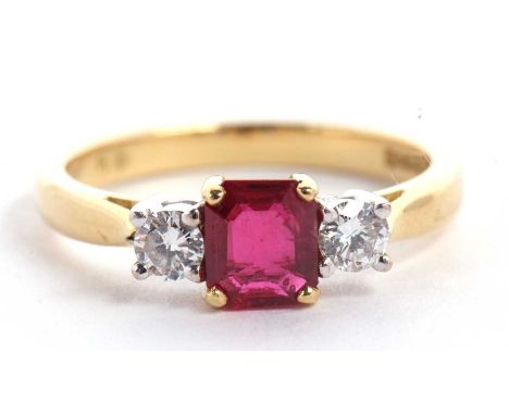 An 18ct ruby and diamond ring, the central emerald cut ruby set to either side with a round brilliant cut diamond, total esti