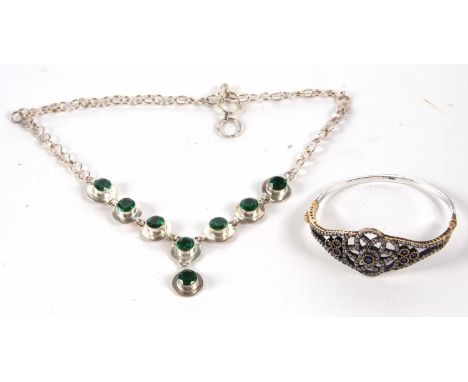A silver gilt and blue and white paste set bangle, the central open fretwork flower set with a blue stone to centre and surro