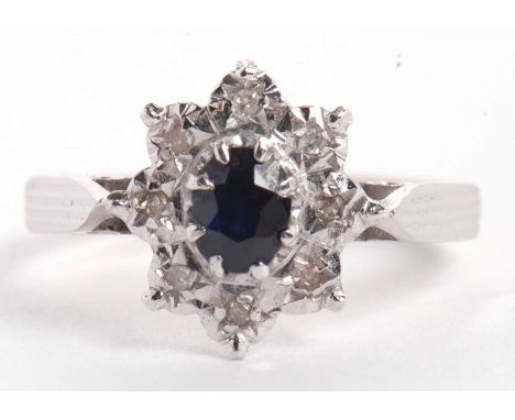 An 18ct sapphire and diamond ring, the central oval sapphire surrounded by eight small illusion set diamonds, all set in whit