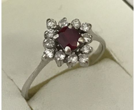 A 14ct white gold ruby and diamond dress ring. Central cushion cut ruby surrounded by 12 round cut 0.02ct diamonds. Total wei