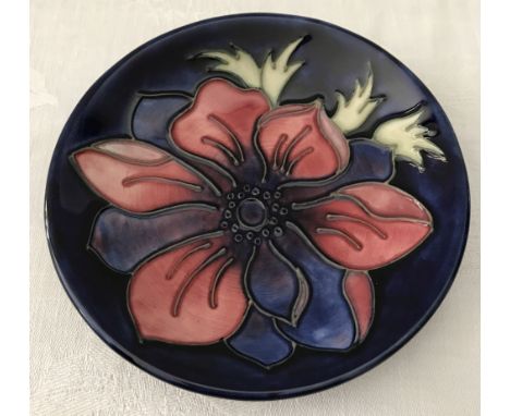 A Moorcroft blue ceramic pin dish with anemone decoration. Impressed stamps to back. Approx. 12cm diameter.
