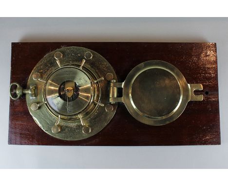 An FCC England barometer with scale 28 to 31 inches and marker and pointer, mounted in a ship's brass porthole, on wooden pan