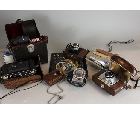 An Arco CR8 cine camera in case, a Kodak folding camera in leather case, three other cameras, a compass and a light meter