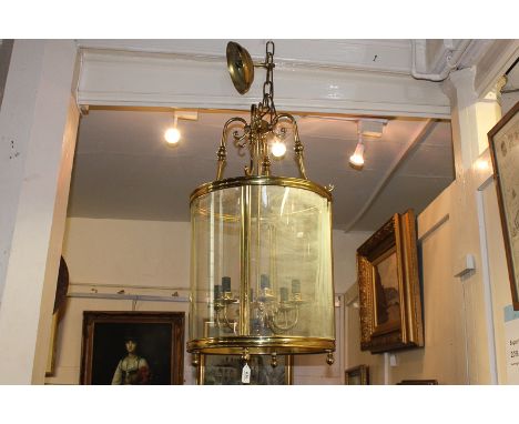 A large circular brass and glass hall/porch light with six bulb holders on scroll brackets, 86cm drop by 44cm diameter