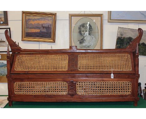 An Indian carved hardwood ceremonial wedding chest with cane panel sides and arched lifting top, four corner finials and shap