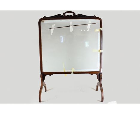 An Edwardian mahogany fire screen with clear glass panel on splayed legs