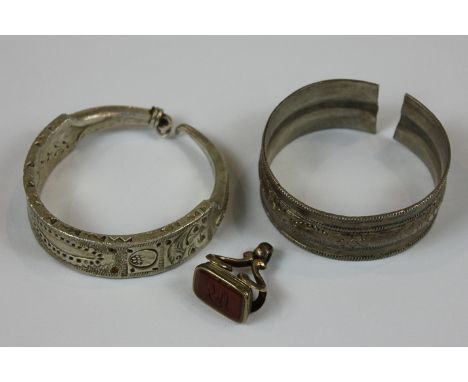 A North African silver open end bangle, a North African silver large hoop earring and a gold cased cornelian fob seal