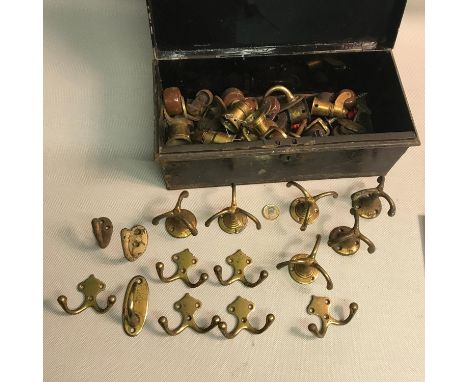 A Metal storage box containing a quantity of antique brass coat hangers and castor (ceramic)feet. 