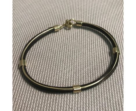 A 14ct gold bangle designed with hair like effect attached round the bangle. Weighs 9.82grams 