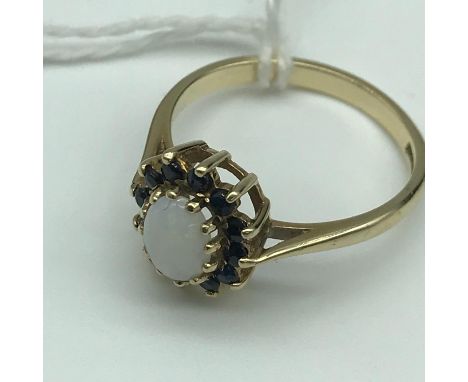 A Beautiful 9ct gold ladies ring set with a single opal and surrounded by a Sapphire cluster. Size N. 