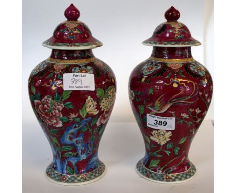 A late 19th/early 20th Century French enamel painted lustre form lidded vase decorated upon a cranberry red ground (2)