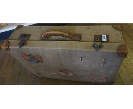 A Vintage canvas suitcase with assorted shipping labels.